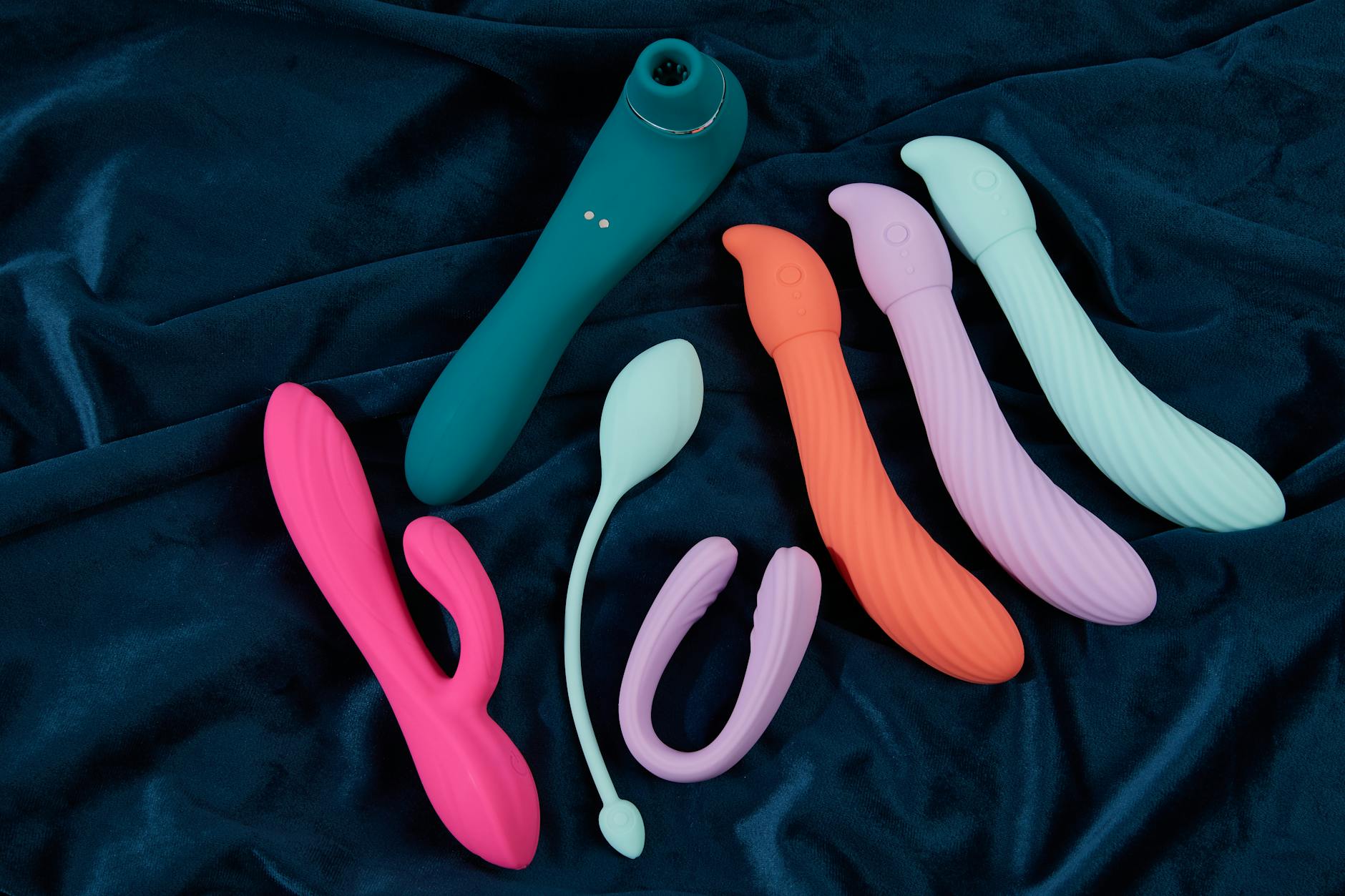 Hand holding a blue clitoral vibrator against a purple background, symbolizing reclaiming pleasure and self-care
