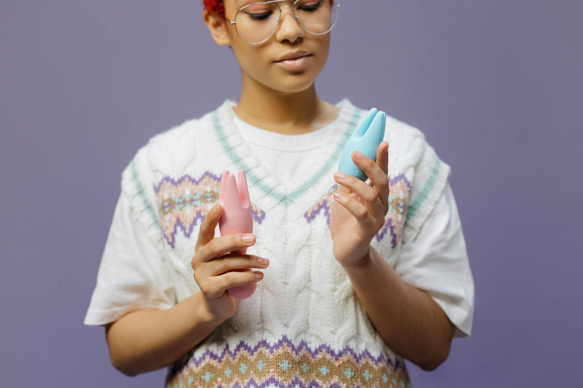 Woman holding blue and pink silicone vibrators in contemplative moment of rediscovery
