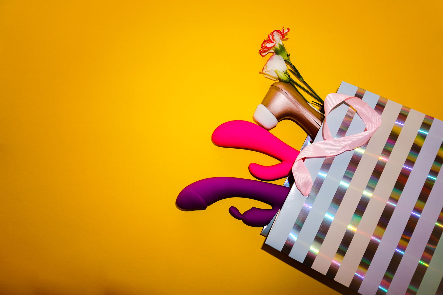 A hand holding a blue vibrator against a neutral background, representing mindful pleasure and recovery.